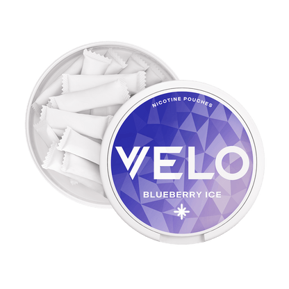 Un envase redondo blanco VELO Blueberry Ice con tapa geométrica azul y morada, parcialmente abierto para revelar pequeñas bolsitas blancas. Disfruta una experiencia refrescante de nicotina con sabor a arándano.