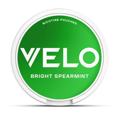 Un envase redondo blanco con tapa verde brillante etiquetado "VELO Bright Spearmint" contiene bolsitas de nicotina con sabor a mentol, elaboradas con ingredientes de origen vegetal.