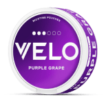 Un envase redondo de bolsitas de nicotina VELO en el sabor Uva Morada, con una llamativa etiqueta morada con texto blanco y elementos de diseño en la tapa y el lateral.