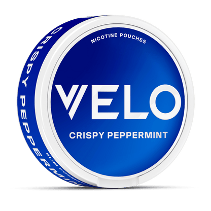 Se muestra en ángulo un envase redondo azul y blanco de VELO Crispy Peppermint con la etiqueta "Nicotina Mentolada Pouches", elaborado con ingredientes de alta calidad para una experiencia refrescante.