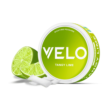Un envase redondo verde de VELO Tangy Lime con texto en blanco y en negrita aparece junto a dos mitades de lima y dos bolsitas blancas sobre fondo blanco, destacando su nicotina afrutada y su origen vegetal.