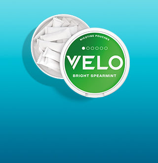 Una lata redonda con la etiqueta Velo Bright Spearmint y tapa verde se abre para revelar varias bolsitas de nicotina blanca en su interior, sobre un fondo azul degradado.