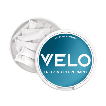 Un envase VELO redondo y blanco etiquetado como Freezing Peppermint con una tapa parcialmente abierta revela varias bolsitas blancas en su interior, que suministran una nicotina mentolada (nicotina mentolada) para una experiencia de menta intensa (menta intensa).