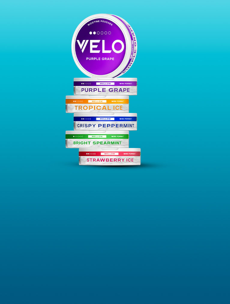 Una pila de coloridos envases de nicotina VELO de varios sabores, como uva morada, hielo tropical, menta crujiente, menta verde brillante y fresa helada, sobre un fondo azul degradado.