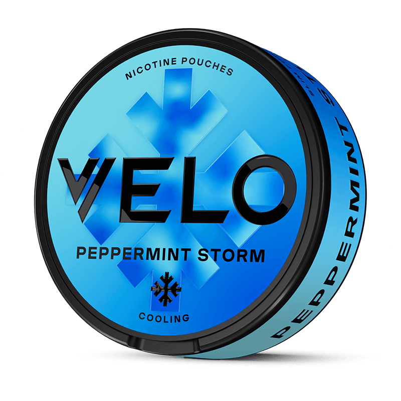 Una lata redonda azul etiquetada VELO Peppermint Storm presenta gráficos de cristal de hielo, las palabras "Nicotina mentolada", "Cooling" y "sabor a menta intensa" en el lateral.