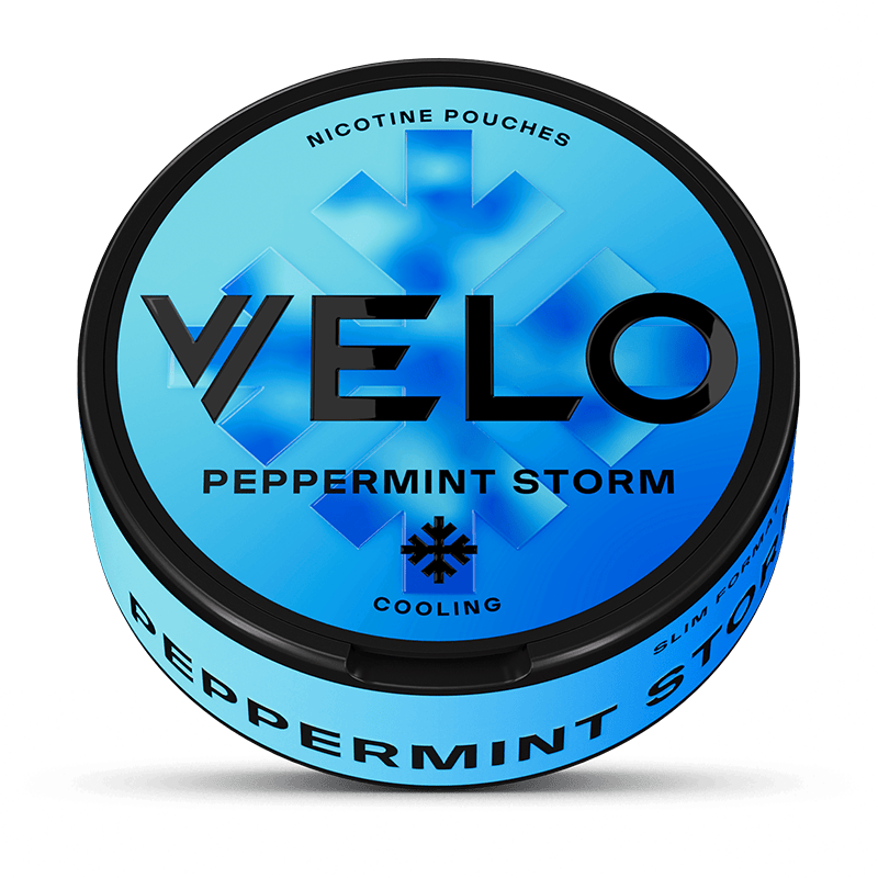 Una lata VELO redonda y azul etiquetada como Peppermint Storm con texto negro en negrita. La tapa muestra un copo de nieve y menciona la nicotina mentolada, mientras que el lateral destaca su intenso sabor a menta.
