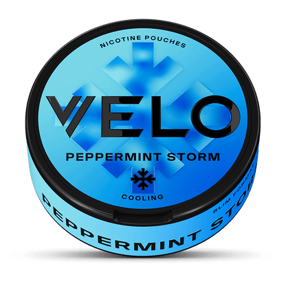 Una lata VELO redonda y azul etiquetada como Peppermint Storm con texto negro en negrita. La tapa muestra un copo de nieve y menciona la nicotina mentolada, mientras que el lateral destaca su intenso sabor a menta.
