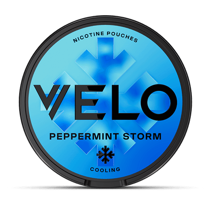 Una lata redonda de VELO Peppermint Storm con fondo azul, gráficos de cristales de hielo y texto negro en negrita. Elaborada con ingredientes de origen vegetal e intenso sabor a menta para un toque ultrafresco.