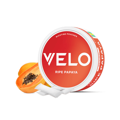 Delante se muestra un envase redondo rojo y blanco de VELO Ripe Papaya con bolsitas de nicotina afrutadas. Detrás del envase hay una papaya madura cortada en rodajas sobre un fondo blanco.