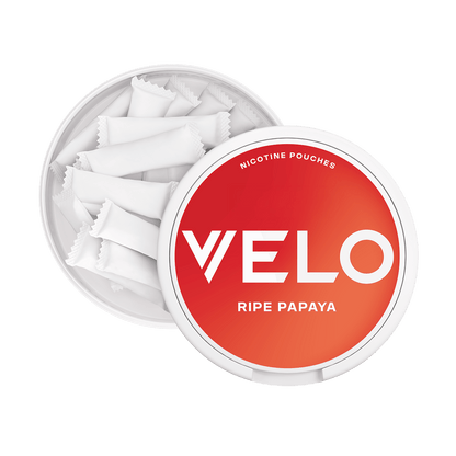 Un envase redondo de color blanco con una tapa de color rojo-naranja etiquetado VELO Papaya Madura, parcialmente abierto para revelar bolsitas de nicotina rectangulares en el interior, ofrece un sabor tropical y una experiencia de nicotina afrutada.