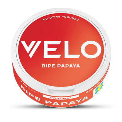 Un envase redondo y blanco con tapa roja etiquetado como VELO Papaya Madura lleva escrito "Nicotine Pouches Original" en la tapa. El lateral muestra "papaya madura", una bandera sueca, y destaca su sabor a nicotina afrutada tropical.