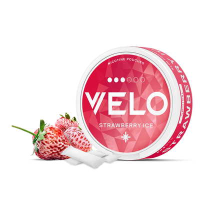 Un envase redondo VELO Strawberry Ice descansa junto a dos fresas y dos bolsas blancas, destacando ingredientes de alta calidad y un intenso sabor a fresa sobre un fondo blanco liso.